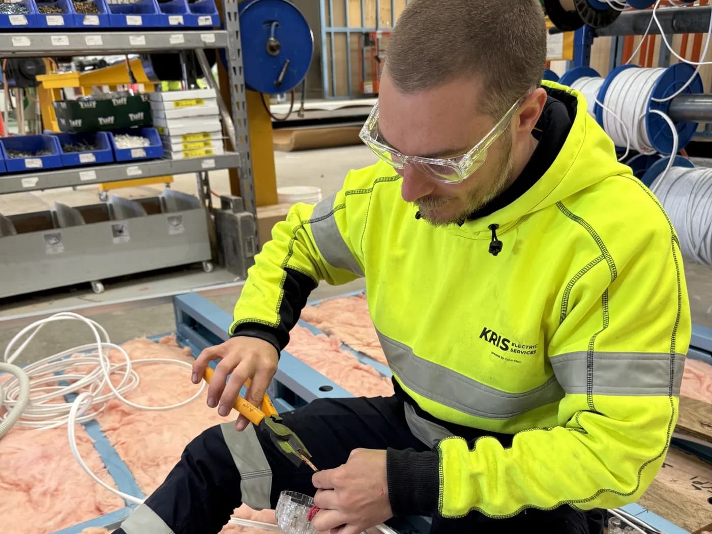 Kris Electrical Services electrician in branded hi-vis making off a light circuit in the ceiling of a modular building during fit-out