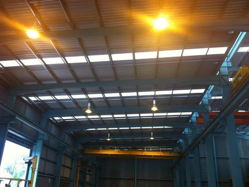 High bay lighting installed through the roof structure of a warehouse with an overhead gantry crane